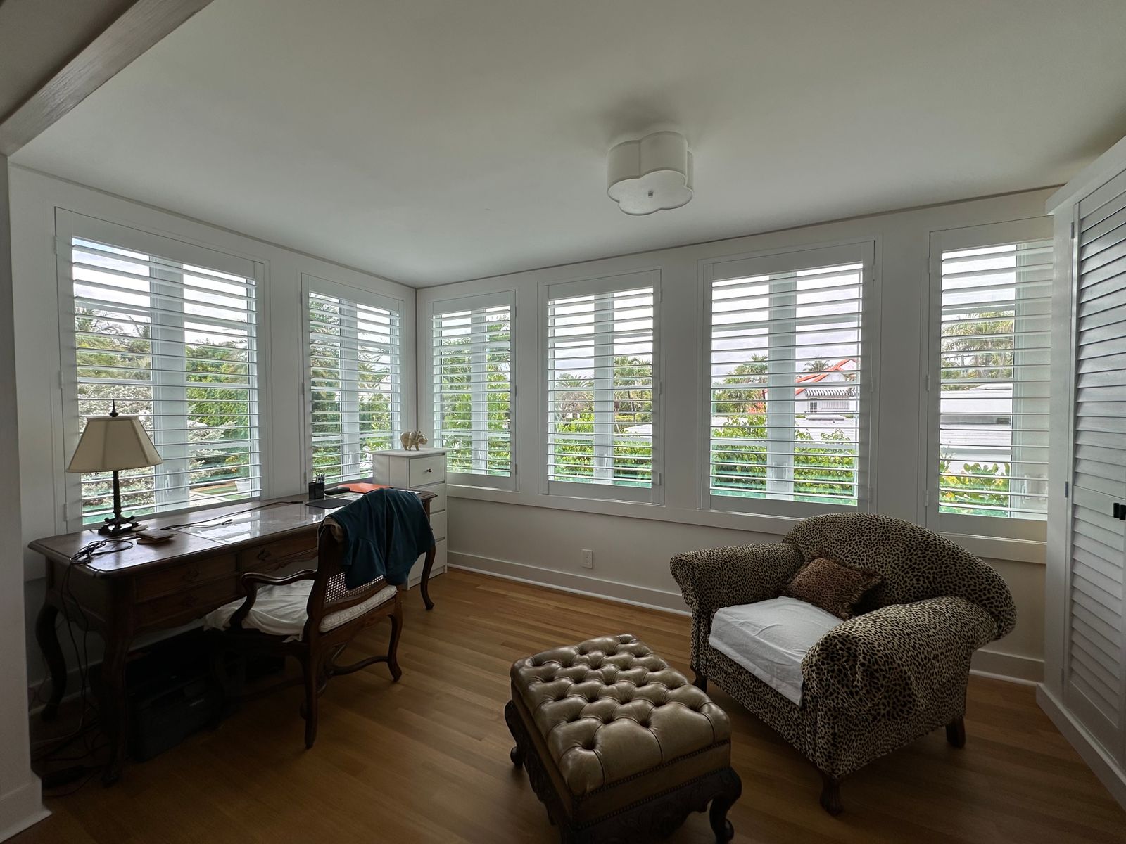 A sunlit office dressed wall-to-wall in white California shutters